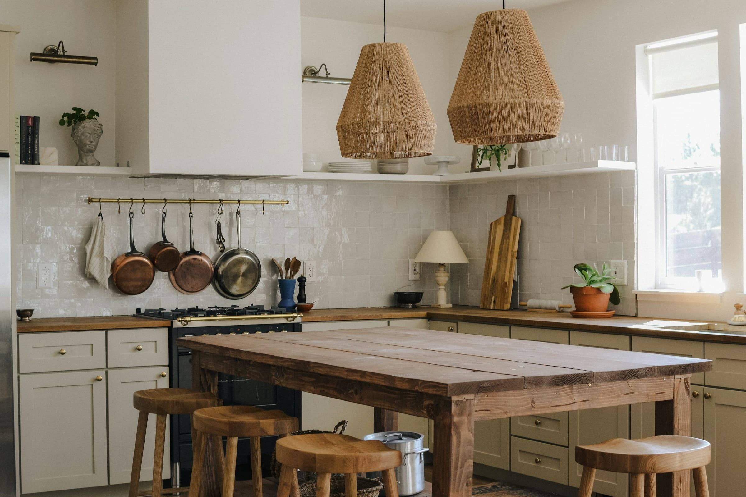 Warm kitchen with rustic timber island, woven pendants and cream cabinetry; wide angle.