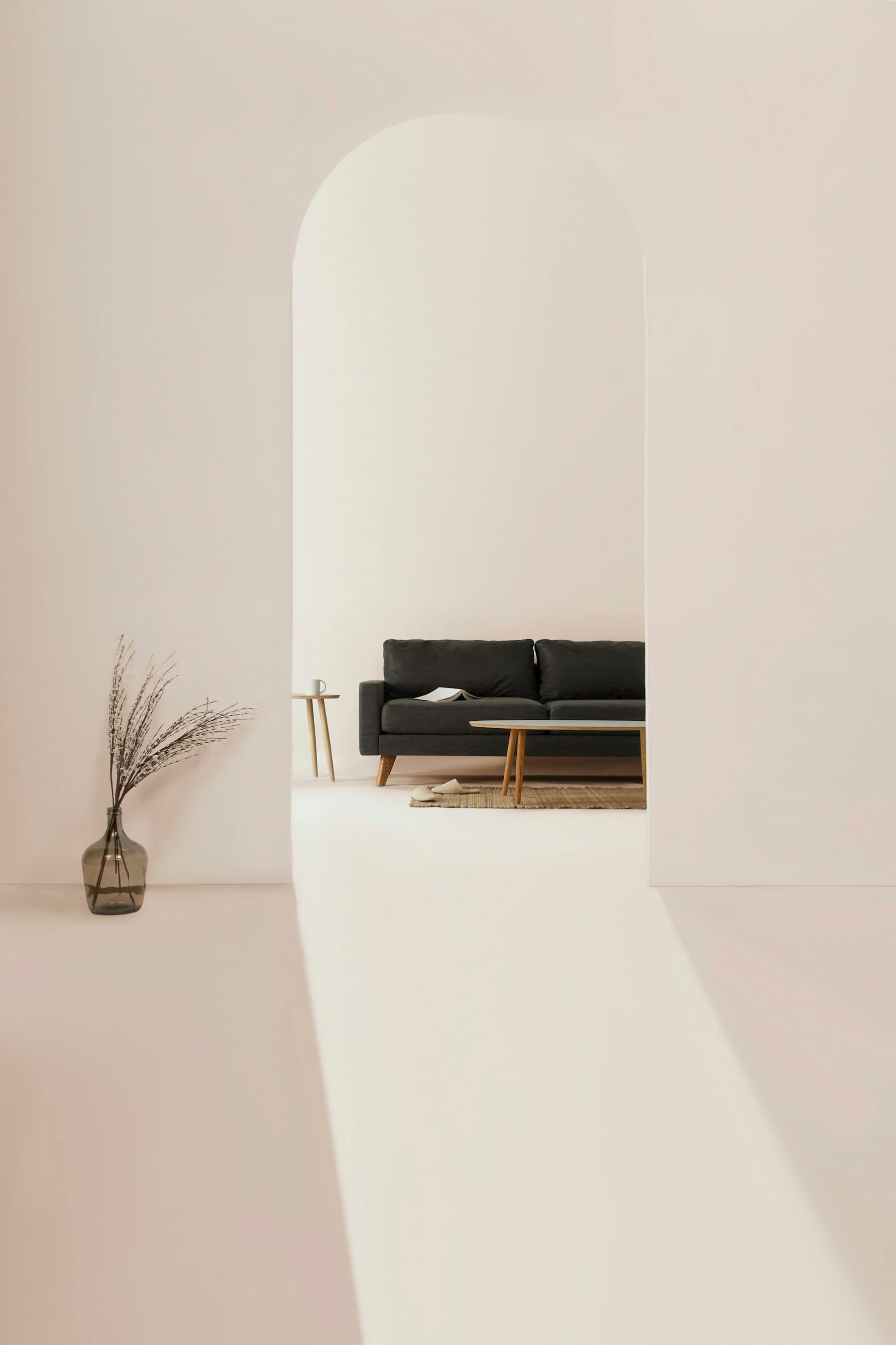 Tall white plaster arch framing a dark sofa and low timber table.