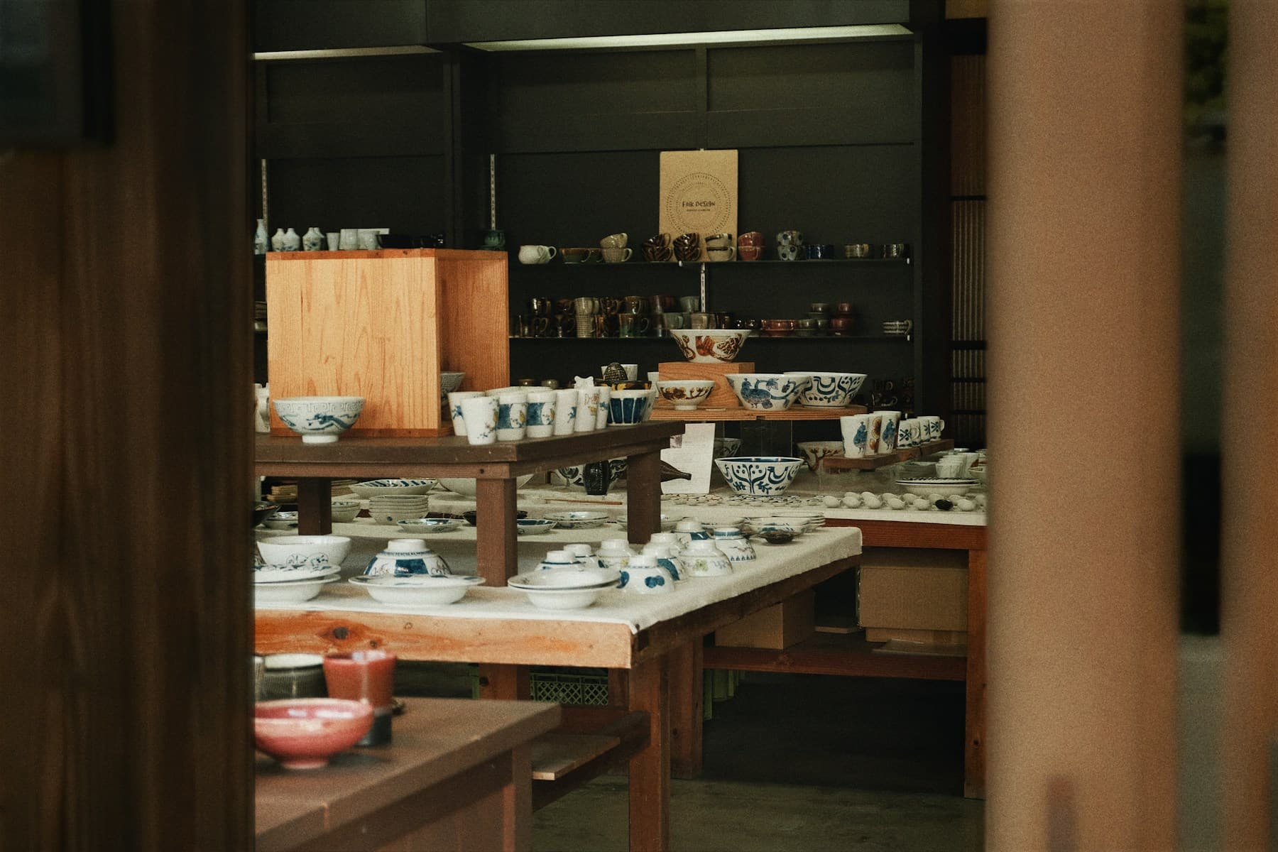 Warm timber shelves and display tables filled with ceramic bowls and plates.
