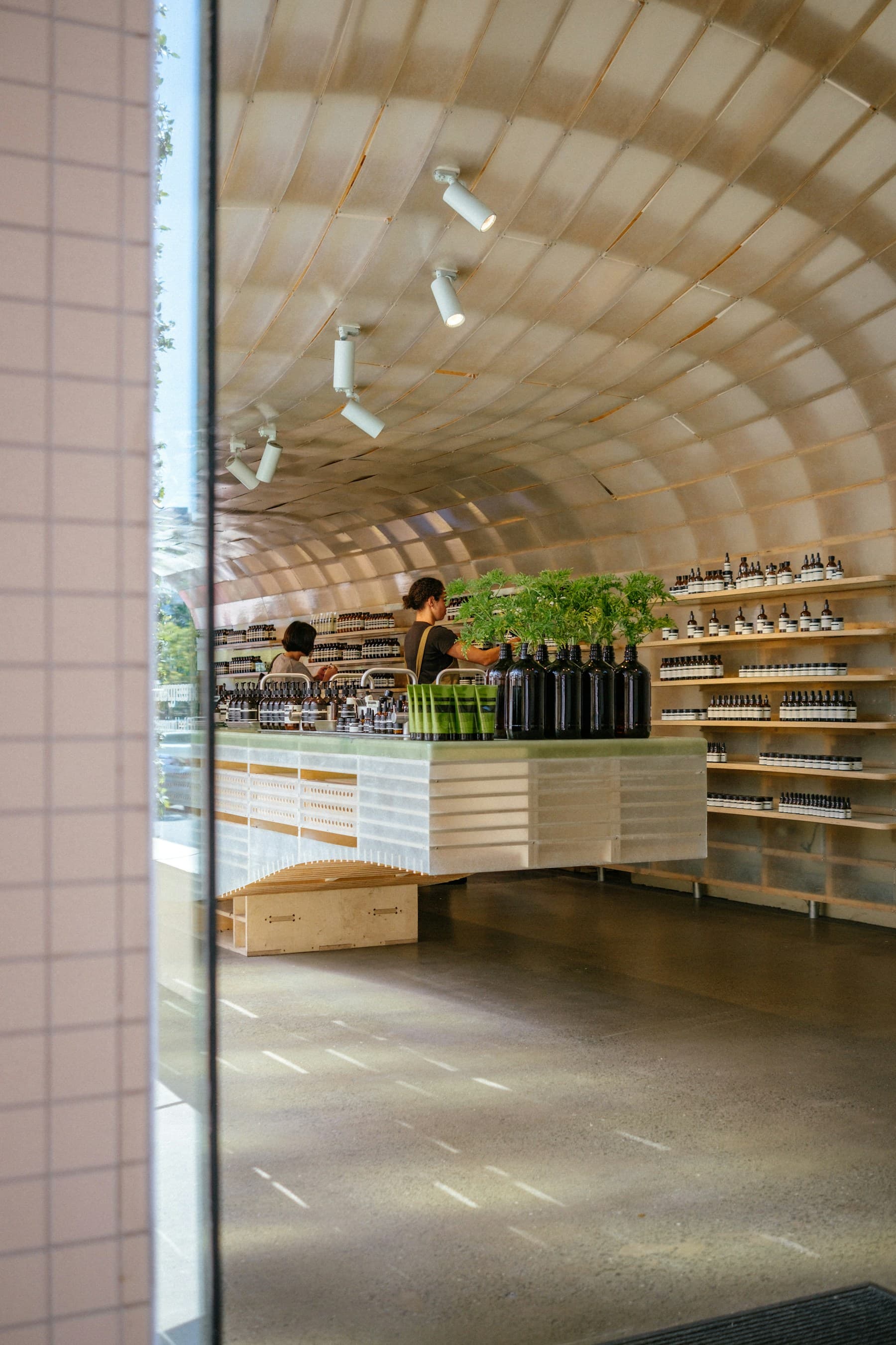 Boutique interior with a curved timber canopy, display island and wall shelving.