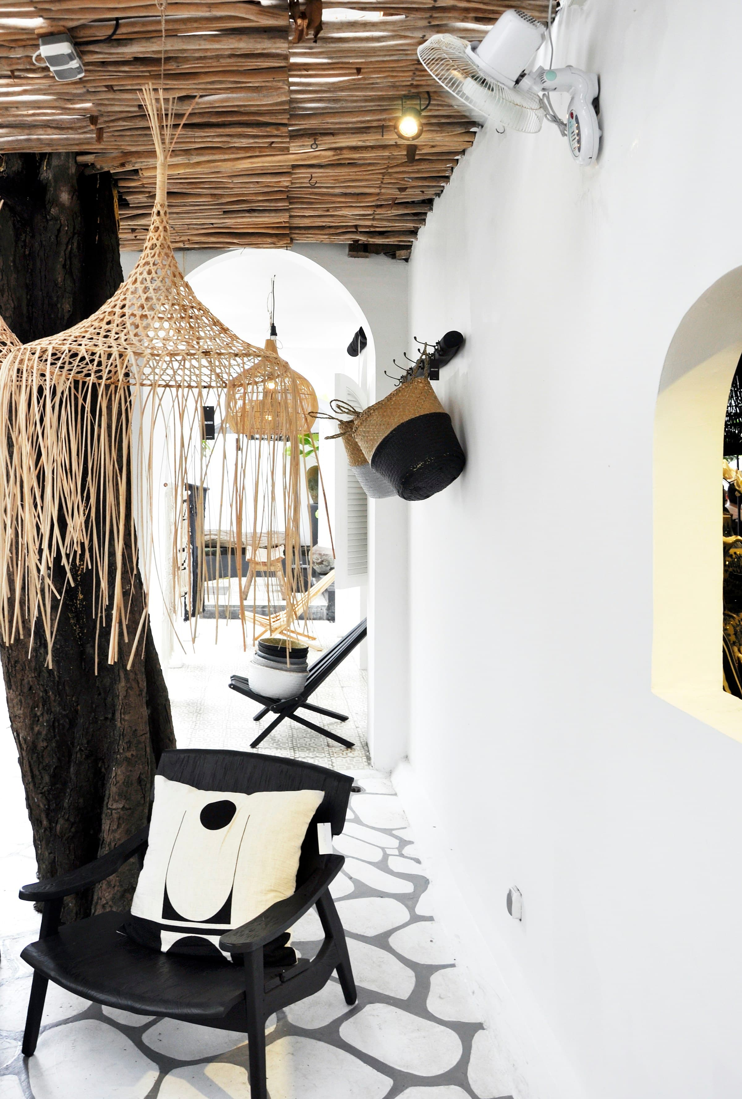 White plaster arches, woven pendant lights and a dark timber lounge chair.