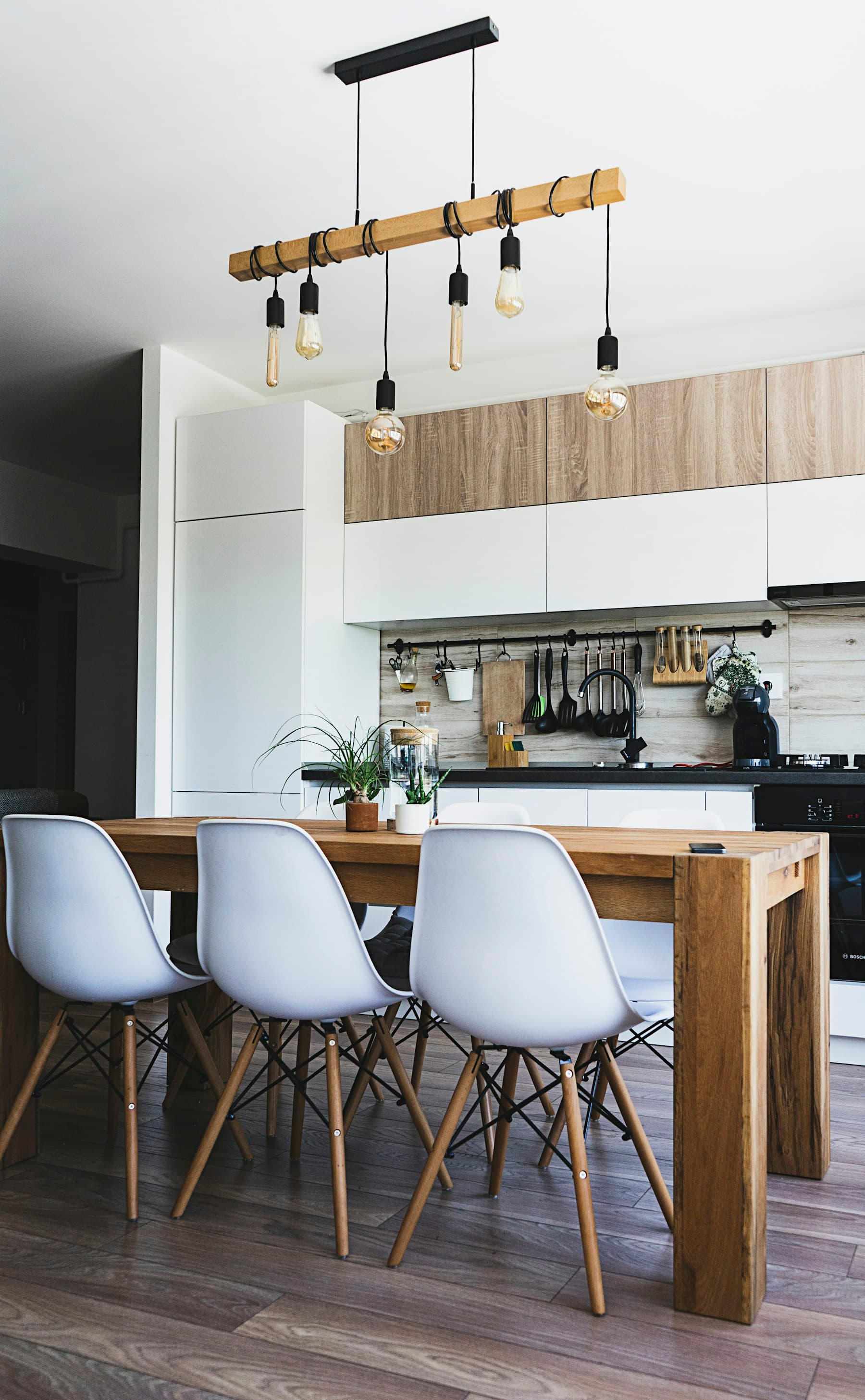 Oak dining table, white chairs and pale timber kitchen cabinetry.